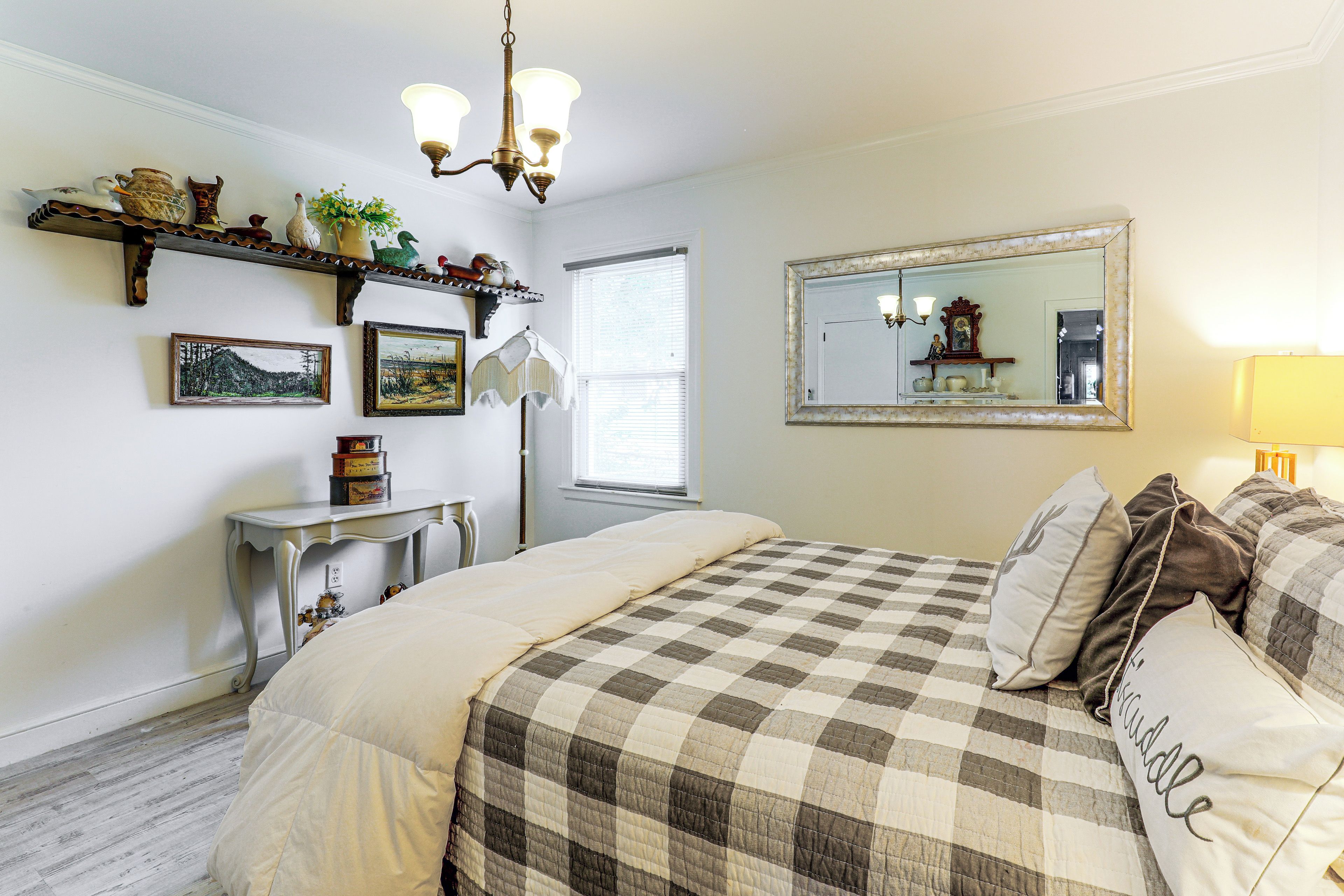 A bedroom with a bed, bedside table, dresser, and a mirror.