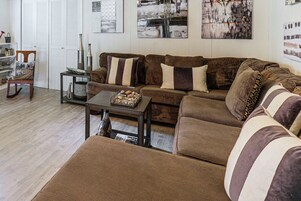 A living room with a brown sectional sofa, a coffee table, and a side table with decorative items.
