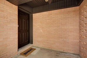 A brick exterior with a dark door and a doormat. - '63 Ag House - 1 Mile from Kyle Field (College Station)