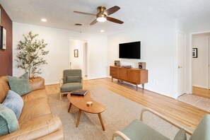 A living room with a sofa, armchair, coffee table, and a television on a stand.
