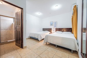 A hotel room with two beds, a wooden door, a tiled floor, and a small wall-mounted light. - Near Beach! Playas del Coco Condo w/ Pool (Sardinal)