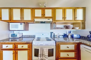 A kitchen with wooden cabinets, a microwave, a stove, and various kitchen appliances. - 2-unit Bundle: Bahia Pez Vela Resort Villas (Sardinal)
