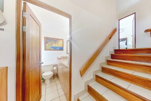 Una escala de fusta amb graons que condueix a una plataforma, una porta de fusta i un quadre a la paret.
