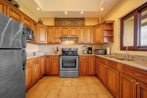 A kitchen with wooden cabinets, a stainless steel refrigerator, a microwave, an oven, and a coffee maker.