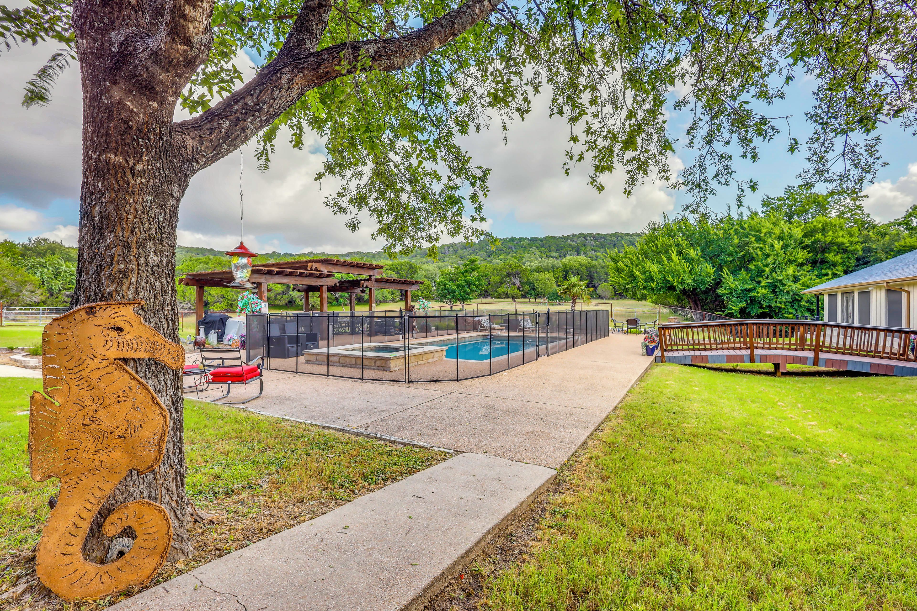 A backyard with a swimming pool, a covered patio area, and a wooden deck.