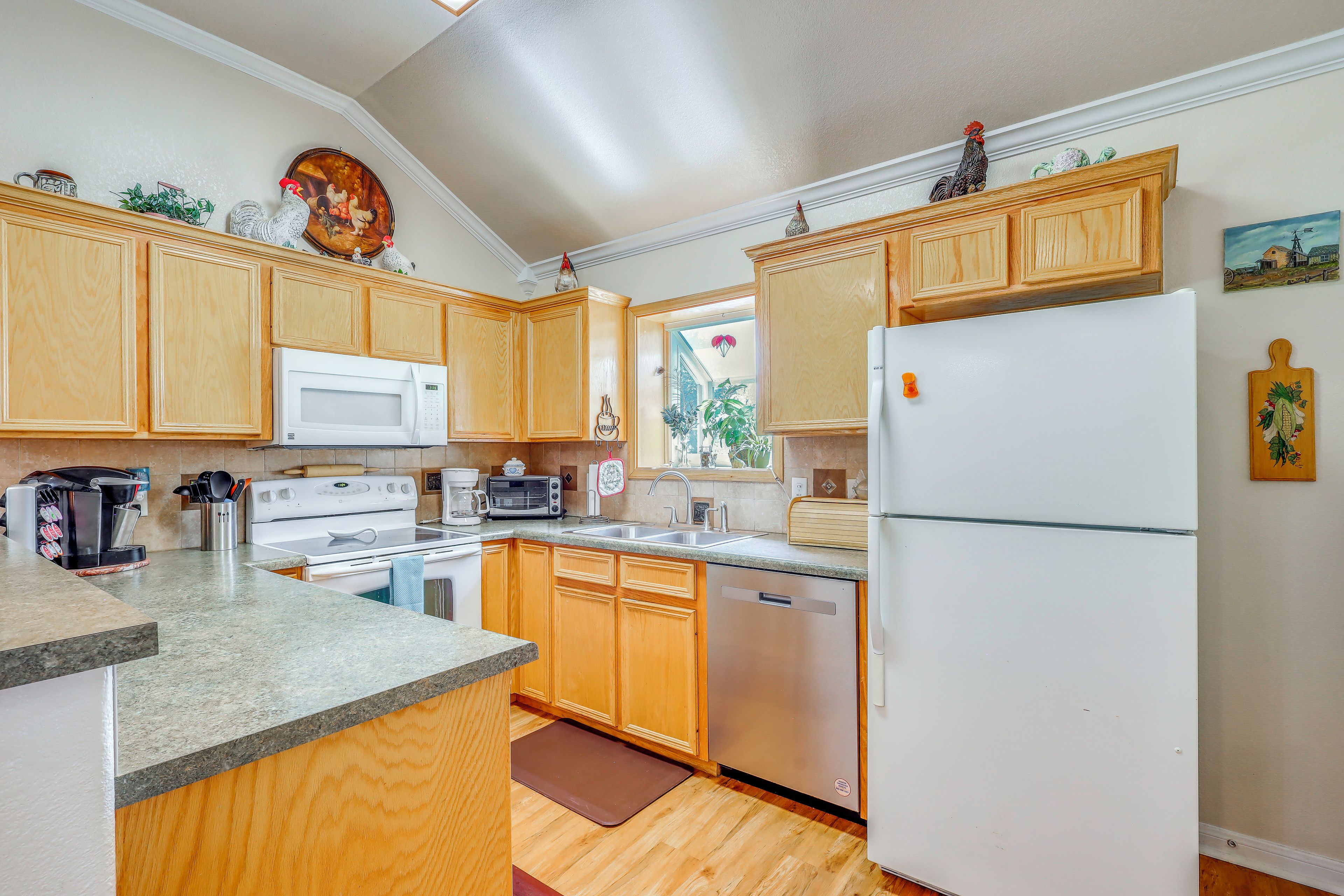 A kitchen with wooden cabinets, a white refrigerator, a microwave, a stove, and a dishwasher.