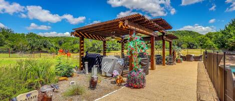 A covered outdoor area with a pergola, seating, and a pool.