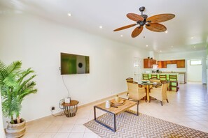 A spacious living area with a dining table, chairs, a ceiling fan, a potted plant, and a kitchen in the background. - Bright 3BR Sunrise Resort 2nd-floor Balcony (Tamarindo)