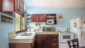 Una cocina con armarios de madera, un fregadero, una estufa, un microondas y un refrigerador.