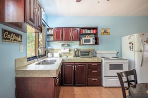 A kitchen with wooden cabinets, a sink, a stove, a microwave, and a refrigerator. - Walk to Playa Ocotal! 2BR Condo w/ Pool (Sardinal)