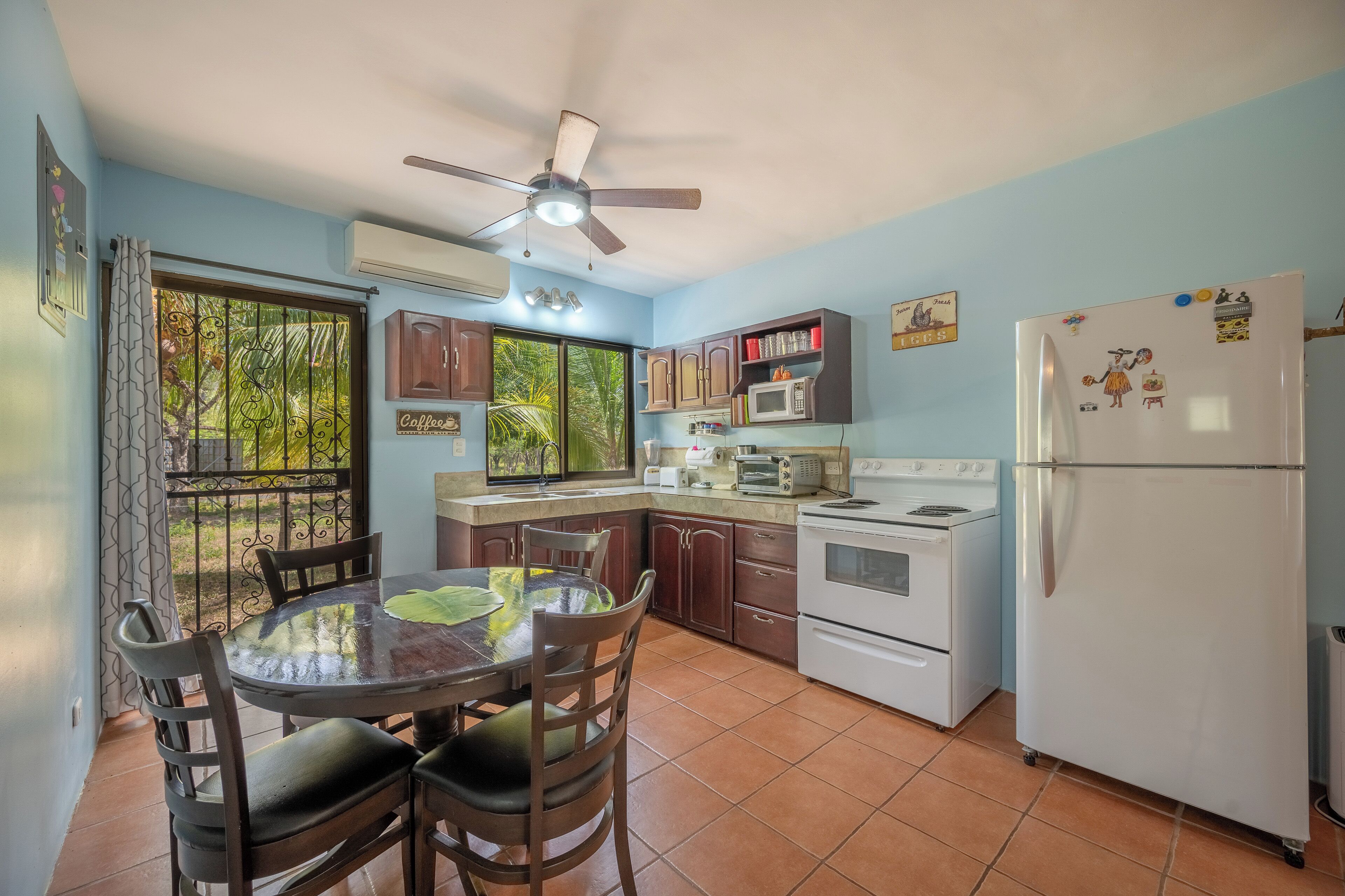 Une cuisine équipée d’une table à manger, de chaises, d’un réfrigérateur, d’une cuisinière et d’un ventilateur de plafond.