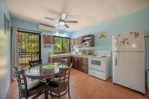 Una cocina con mesa, sillas, refrigerador, estufa y ventilador de techo.
