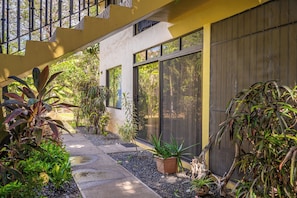 Un edificio moderno con amplios ventanales, un paseo cubierto y diversas plantas.