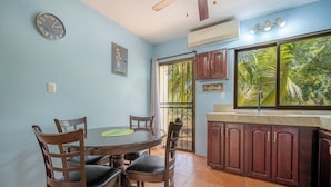 Un comedor con una mesa redonda y sillas, un reloj en la pared y un ventanal con vistas a zonas verdes.