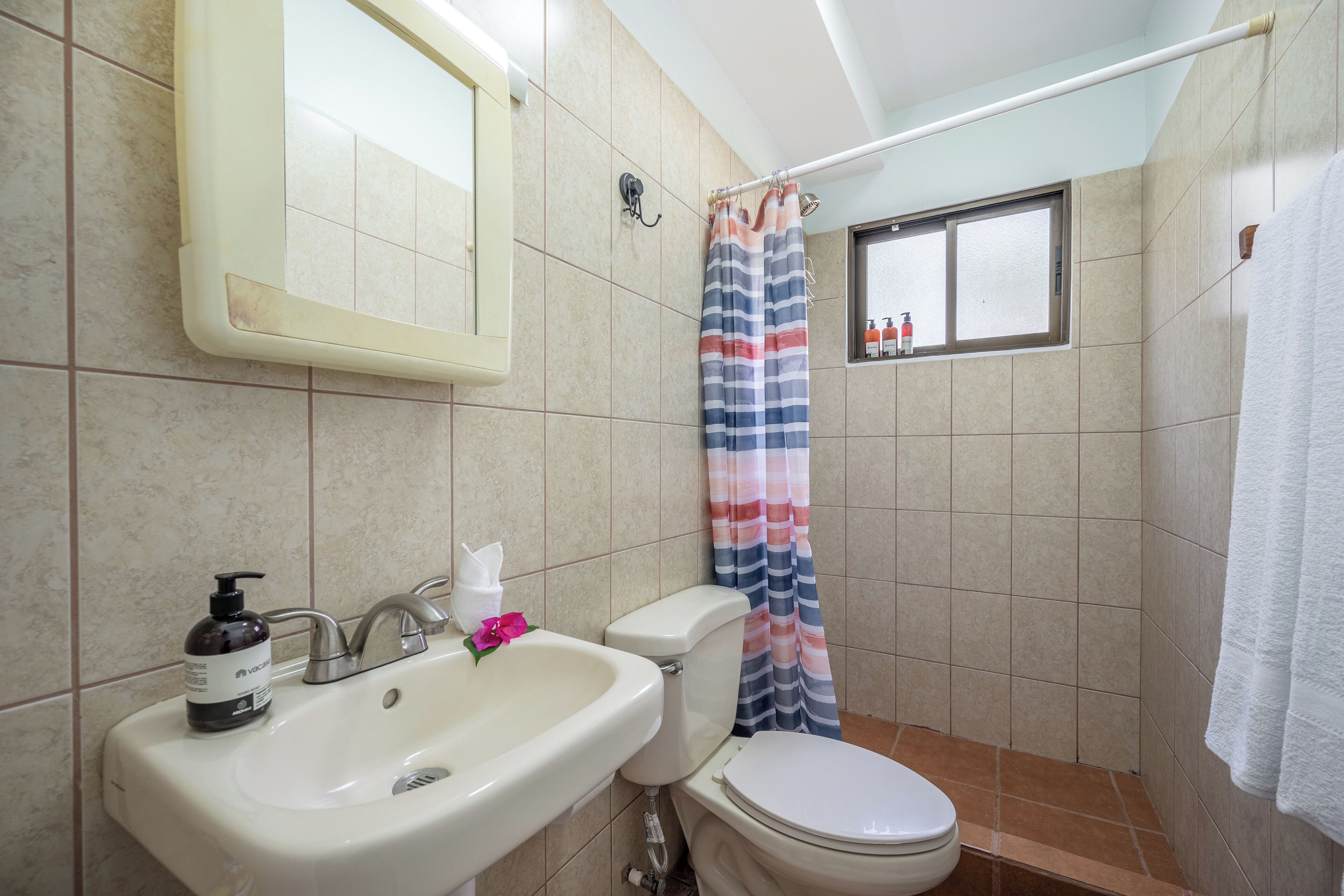 Un baño con lavamanos, inodoro y cortina de ducha.