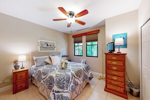 A bedroom with a bed, a nightstand, a dresser, a ceiling fan, a window with blinds, and a wall-mounted TV. - Playas del Coco: Balcony, Near Beaches! (Sardinal)