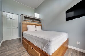 Un dormitorio con estructura de cama de madera, colchón blanco y cabecera integrada.