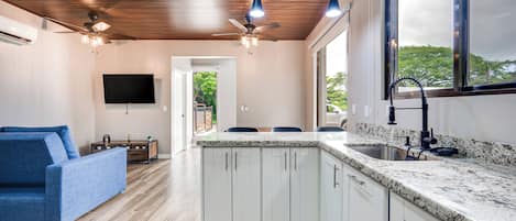 Una cocina moderna con armarios blancos, encimera de granito y un amplio ventanal.