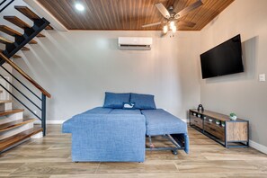 Un dormitorio con cama, televisor, ventilador de techo y una escalera.