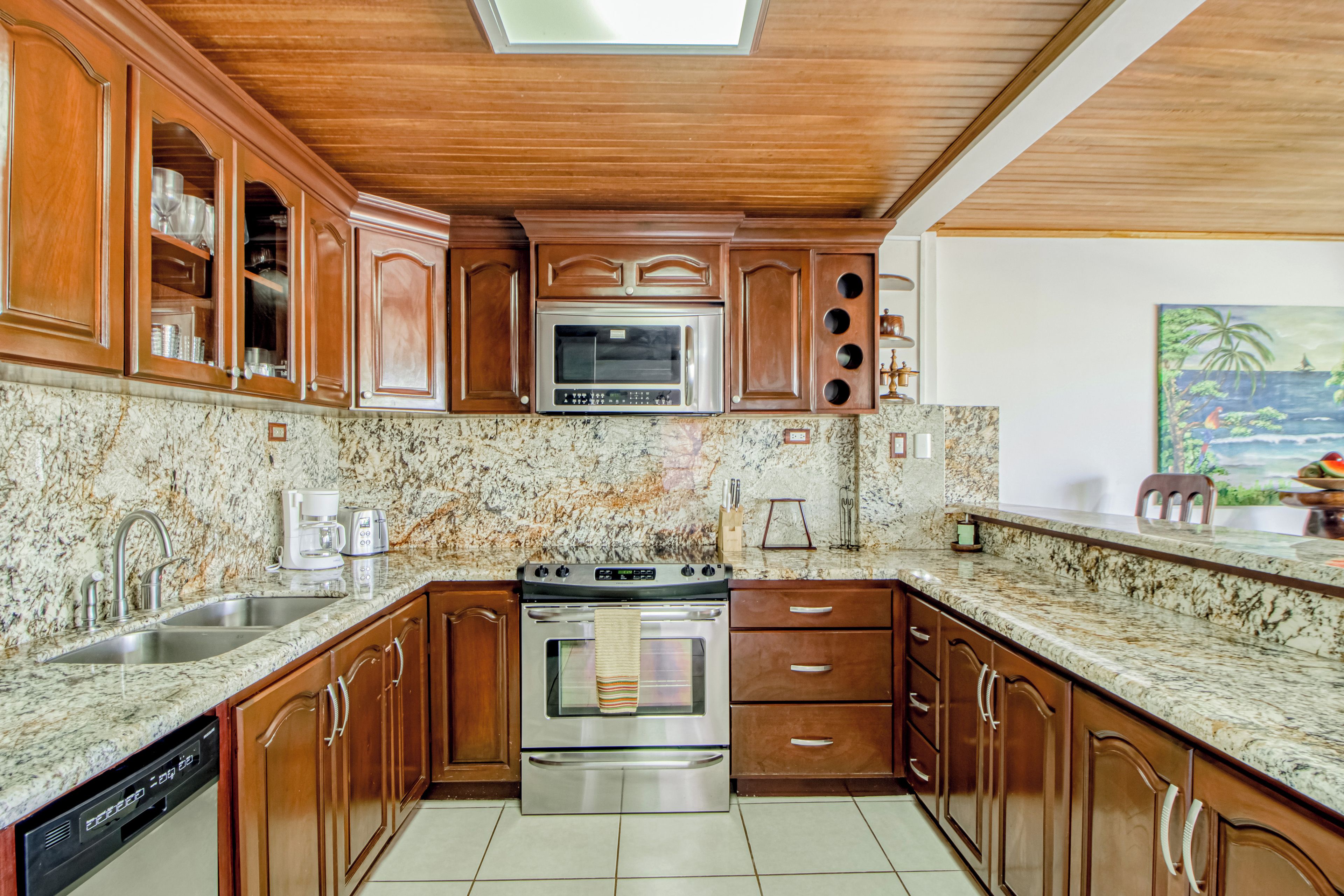 A kitchen with wooden cabinets, a stainless steel oven, and a granite countertop.