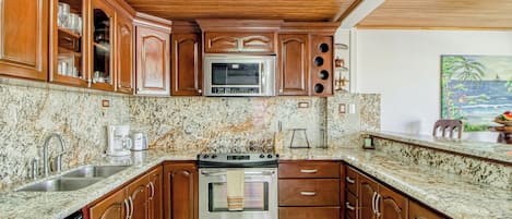 A kitchen with wooden cabinets, a stainless steel oven, and a granite countertop.