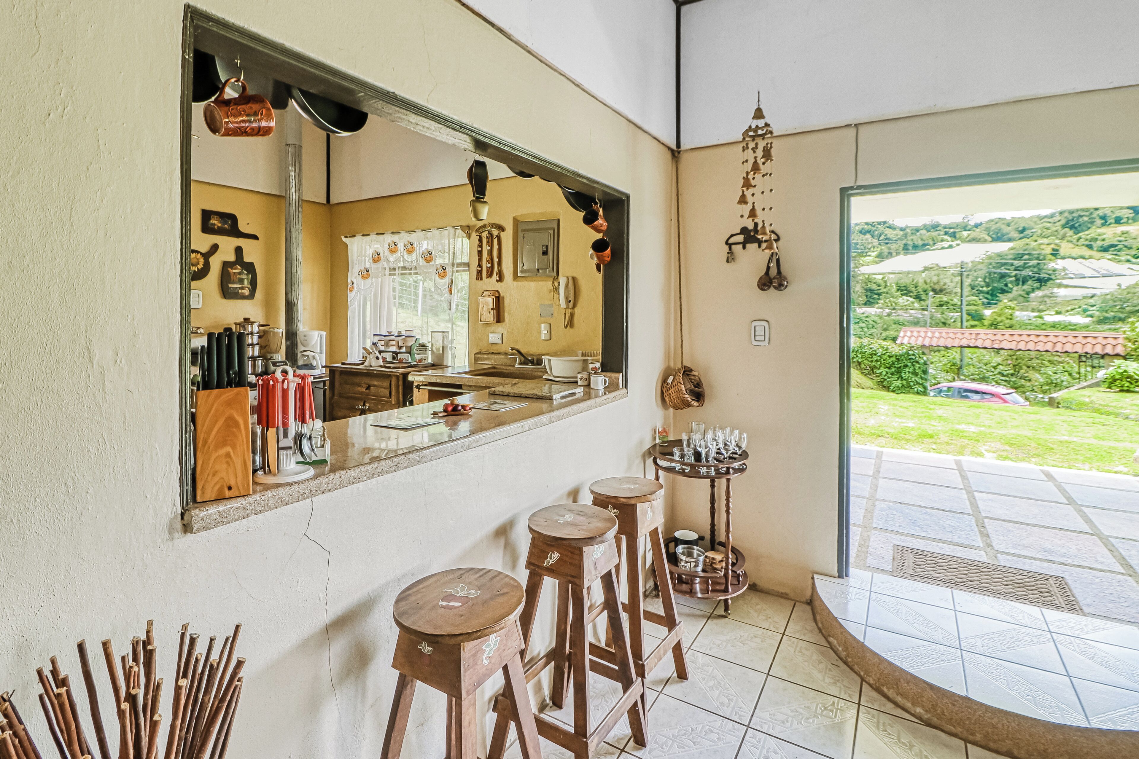 A kitchen with a large mirror, stools, and a view of the outdoors.