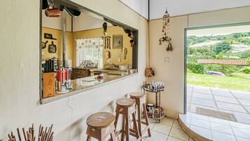 A kitchen with a large mirror, stools, and a view of the outdoors.