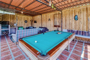 A pool table with a single white ball, surrounded by a checkered tablecloth.