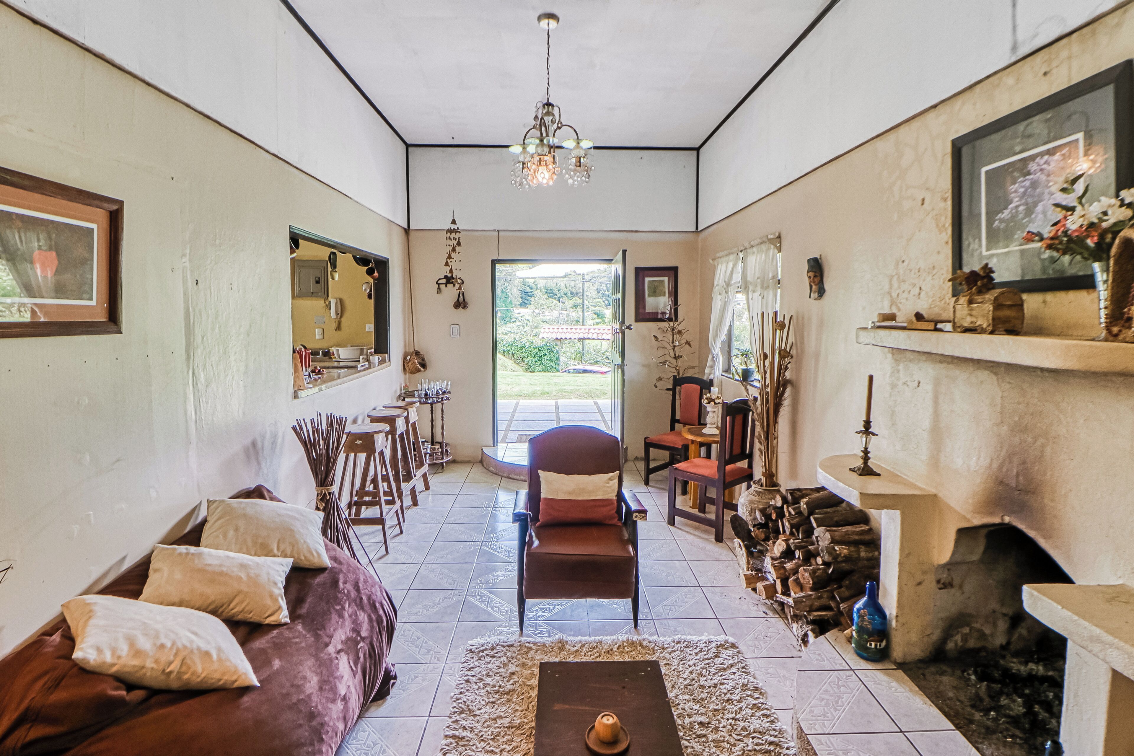 A cozy living room with a sofa, a fireplace, and a dining area with chairs and a table.