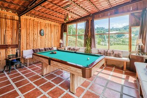 A pool table in a room with wooden walls and large windows.