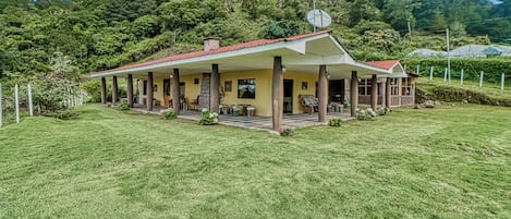 A two-story house with a red roof, multiple columns, and a satellite dish.