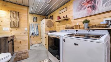 A compact kitchen with a stove, a washing machine, and a large wall-mounted picture.