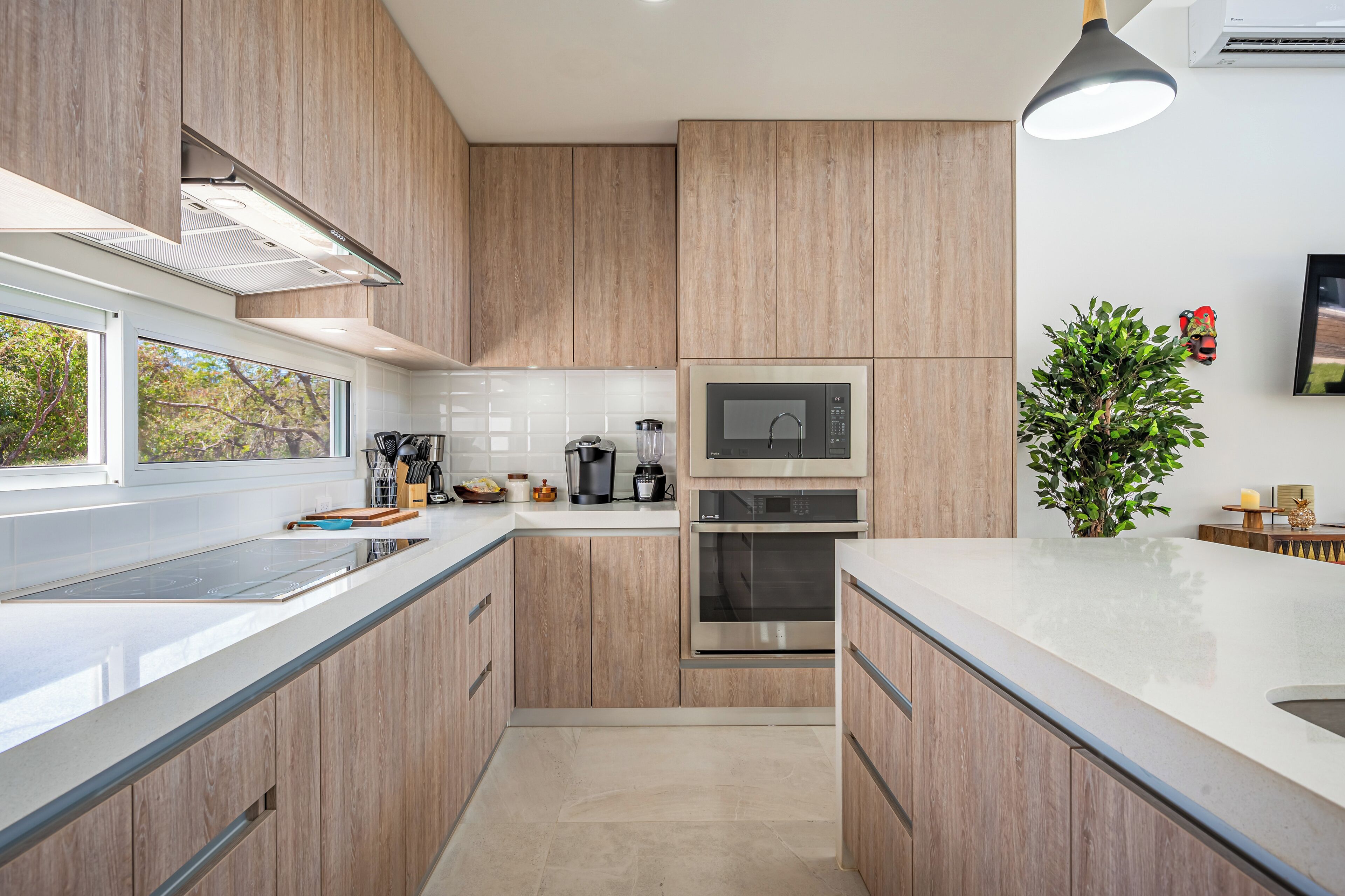 A modern kitchen with wooden cabinets, stainless steel appliances, and a large window.