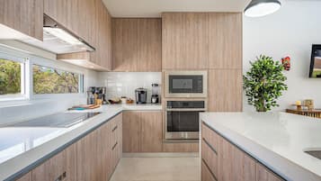 A modern kitchen with wooden cabinets, stainless steel appliances, and a large window.