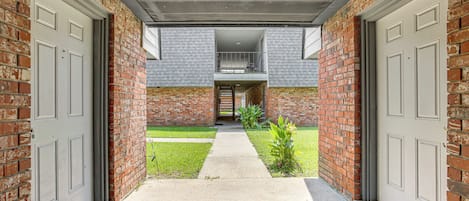 A brick exterior with two garage doors, a concrete pathway, and a small grassy area with plants.