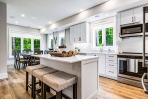 Una cocina moderna con una isla central, electrodomésticos integrados y un comedor con luz natural.