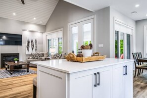 Una cocina moderna con una isla grande, armarios blancos y una zona de comedor con mesa y sillas.