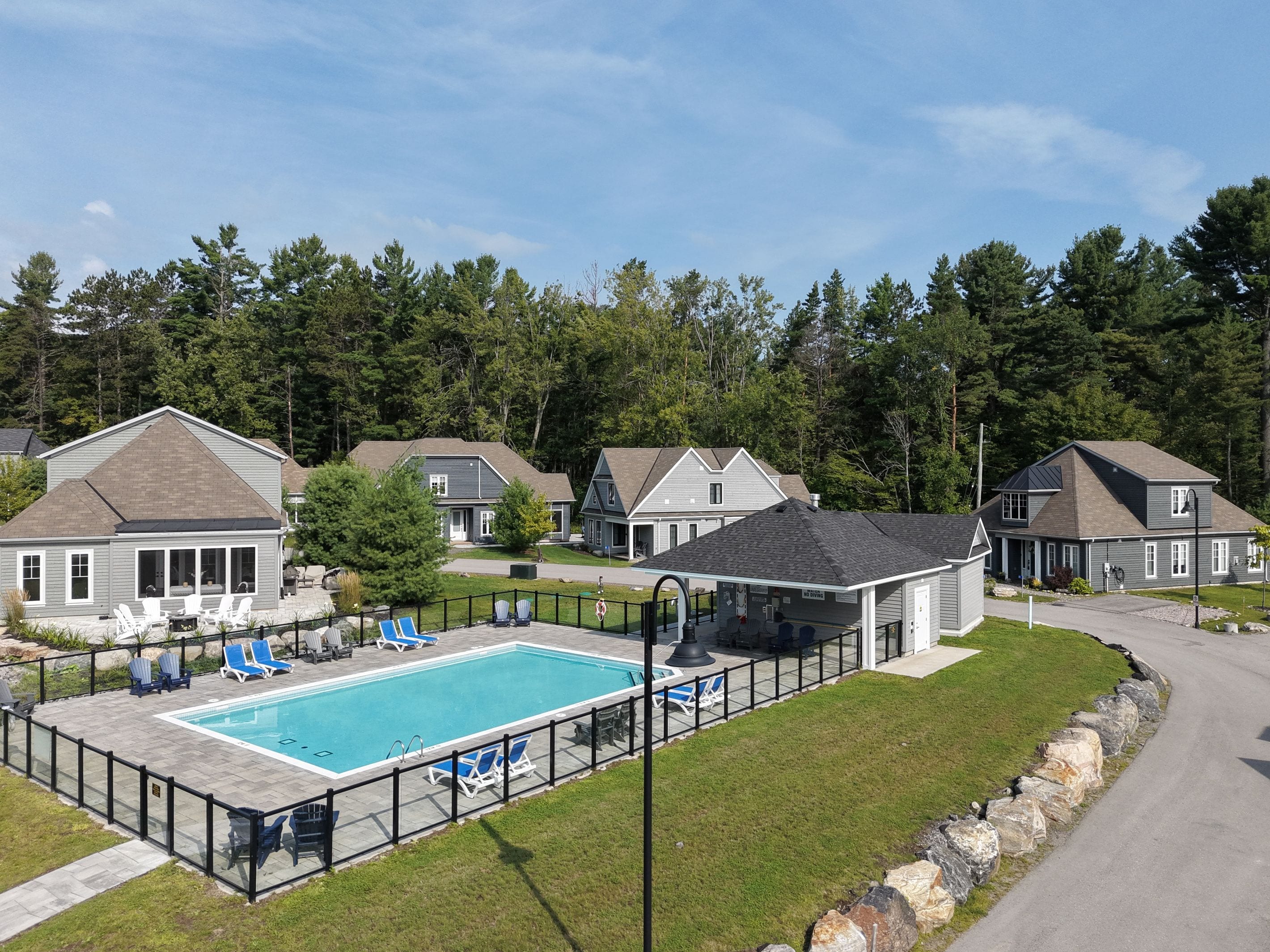 Un quartier résidentiel doté d’une piscine, de chaises longues et de maisons.
