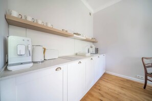 Een moderne keuken met witte kasten, een aanrecht en een houten vloer.
