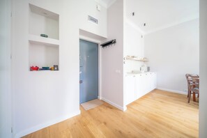 A modern interior with a wooden floor, a kitchen area with white cabinets, and a blue door. - Mostowa Old Town Apartment, Warsaw (Warszawa)