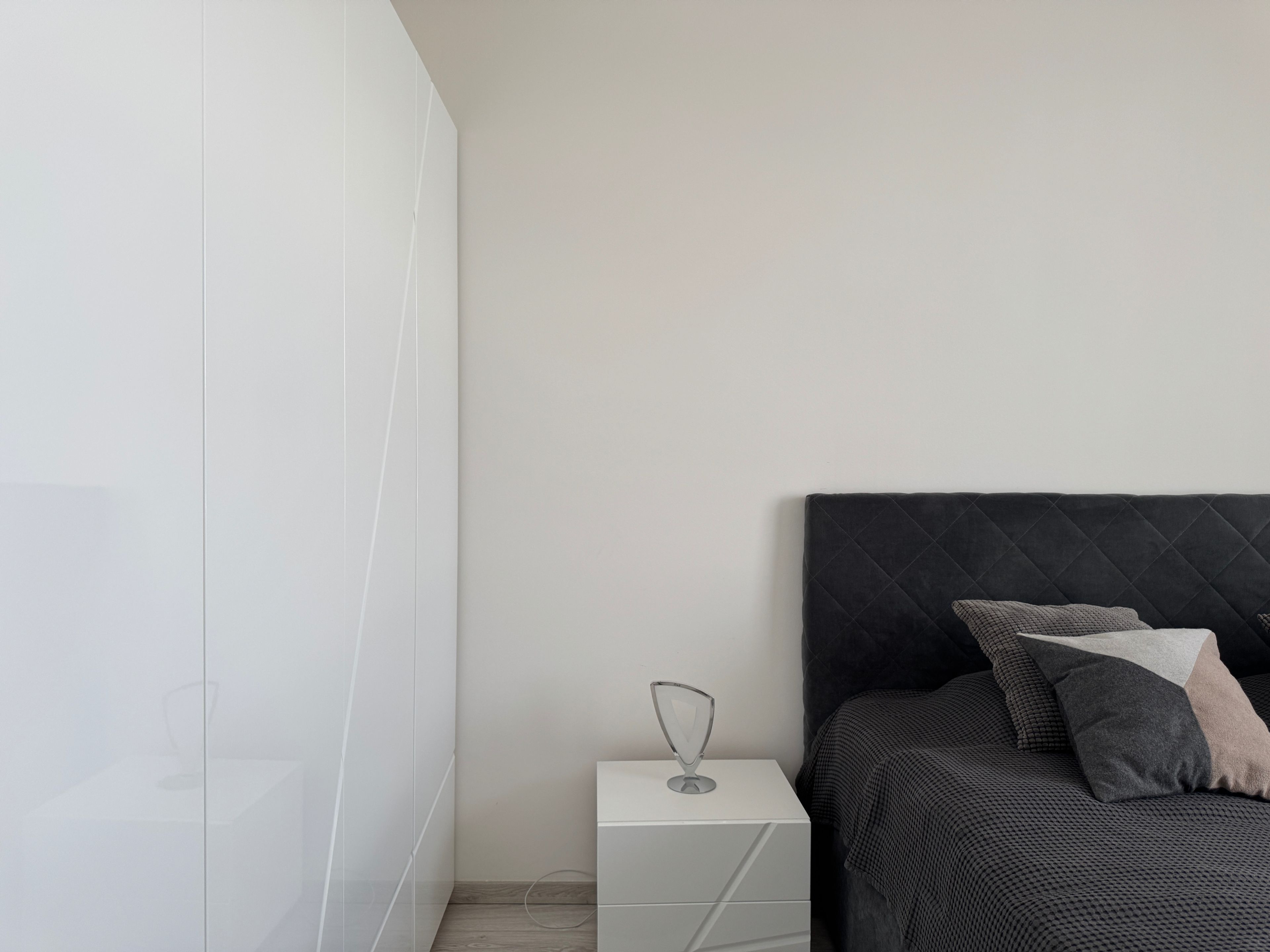 Een slaapkamer met een bed, nachtkastje en een kledingkast.