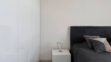 Een slaapkamer met een bed, nachtkastje en een kledingkast.