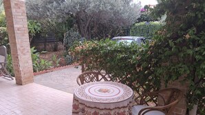 An outdoor patio with a round table, chairs, and a brick pillar.