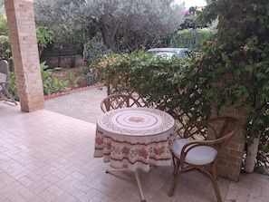 Un patio al aire libre con una mesa redonda, sillas y un pilar de ladrillo.