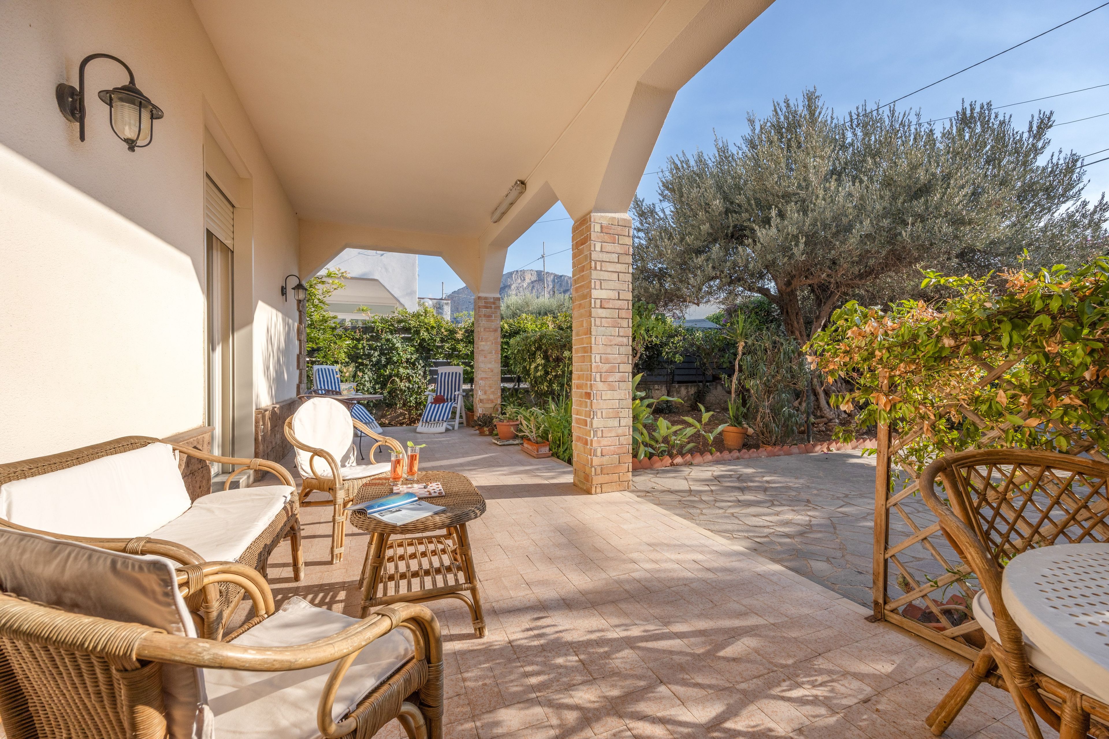 Un patio al aire libre con mobiliario de mimbre, un pilar de ladrillo y vistas del paisaje circundante.