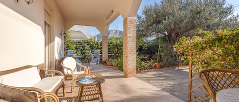 Un espace extérieur aménagé en terrasse, avec des meubles en osier, un pilier en briques et une vue sur le paysage environnant.