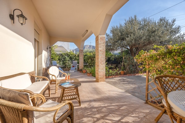 An outdoor patio area with wicker furniture, a brick pillar, and a view of the surrounding landscape.