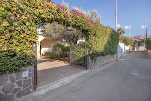 A residential street with a house number 13, a stone wall, and a metal gate.