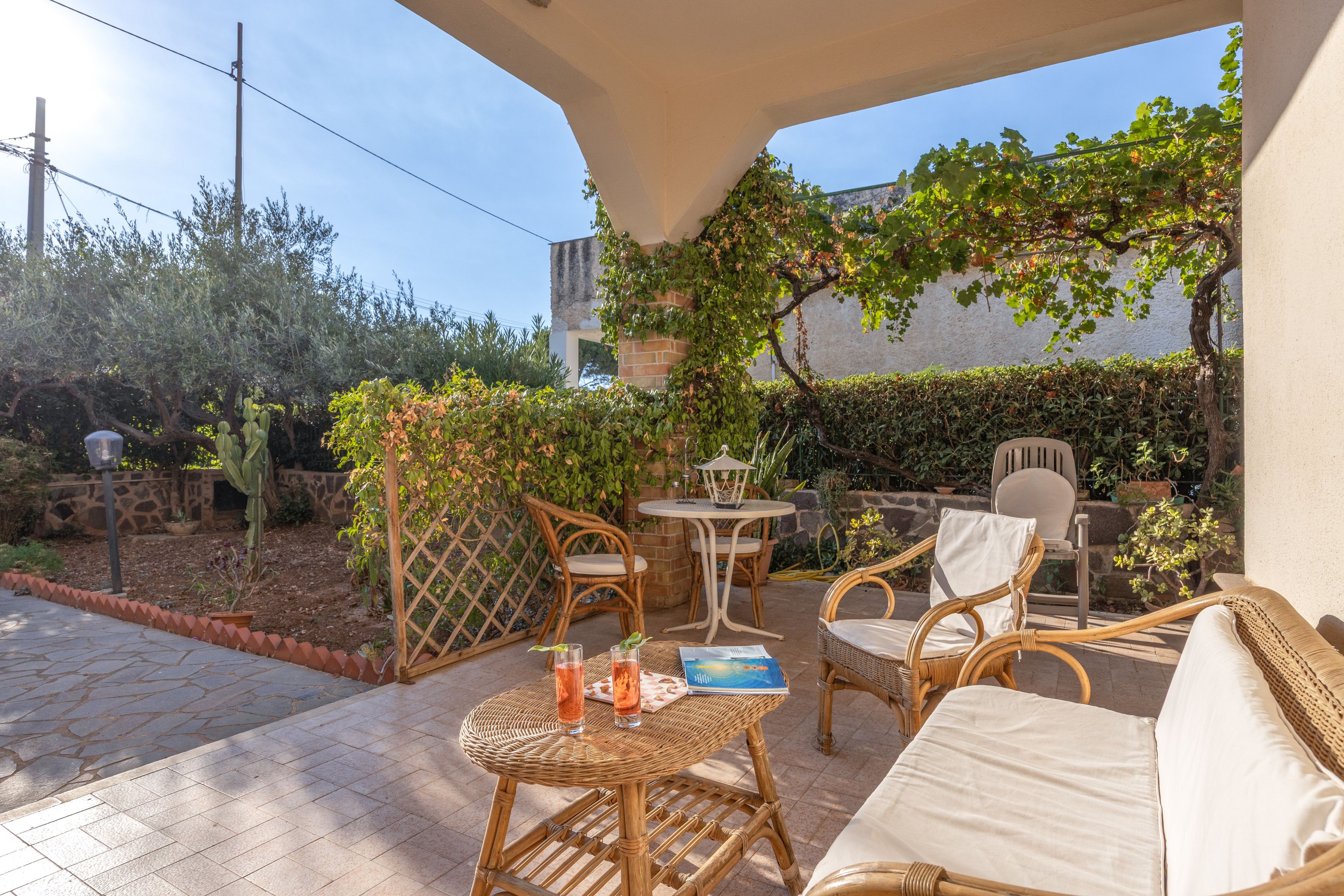 Une terrasse extérieure aménagée avec des meubles en osier, une table et des chaises.