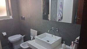 A modern bathroom with a white sink, a toilet, and a shower.
